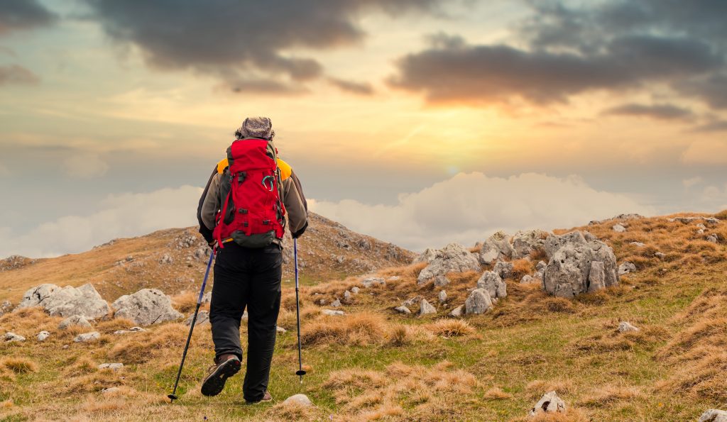 Randonnées en Auvergne : les plus beaux parcours à explorer Vue arrière d'un randonneur regardant le coucher de soleil
