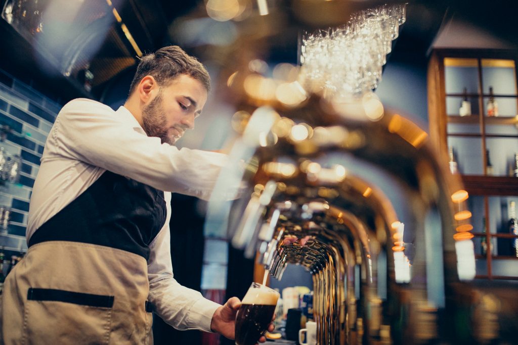 Découvrez les brasseries artisanales d’Auvergne handsome bartender pouring beer in pub