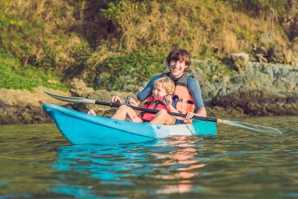 father and son kayaking at tropical ocean.