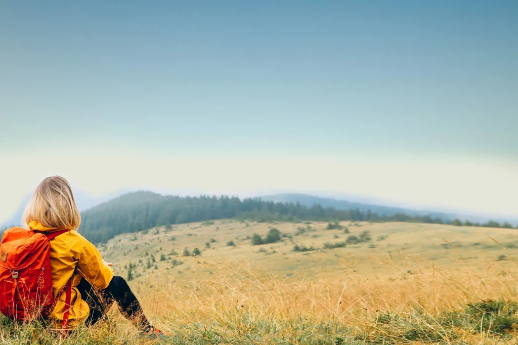Le Puy de Sancy, une randonnée incontournable au cœur de l’Auvergne Personne de dos assise contemplant un paysage d'Auvergne